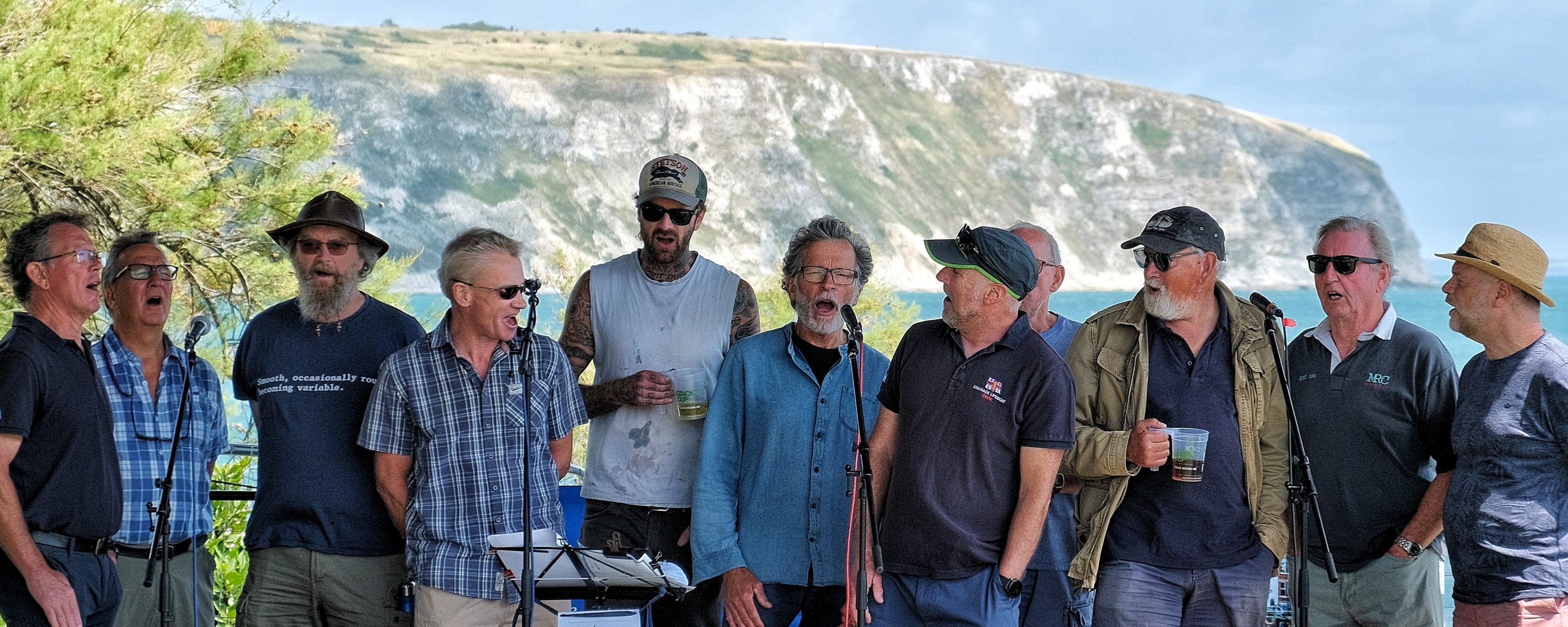 A shanty crew singing on the Swanage seafront in front of the white cliff